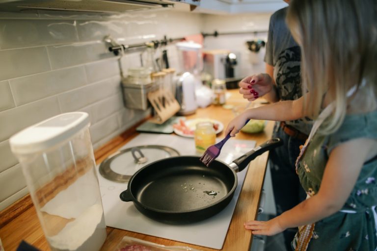 Pige laver mad på en pande sammen med sin far